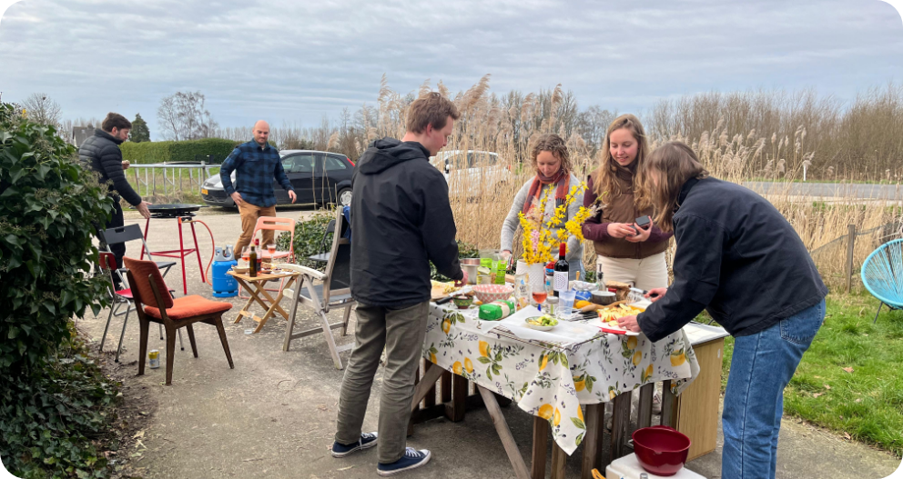 Bewoners en geïnteresseerden rond een gedekte tafel in de buitenlucht